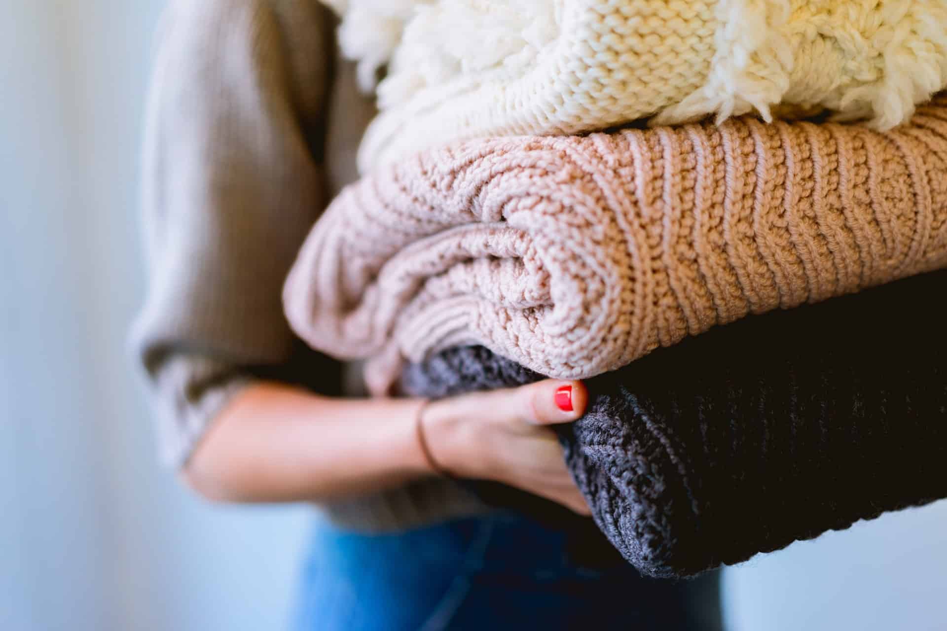 person holding stack of folded clothes