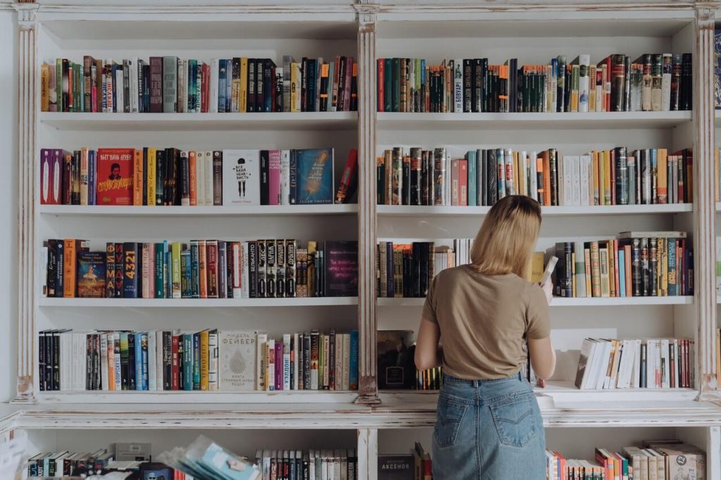 Woman looking at books organized on a shelf in a living room