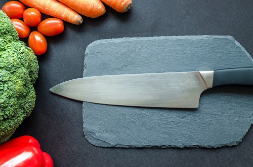 knife and cutting board surrounded by fresh veggies