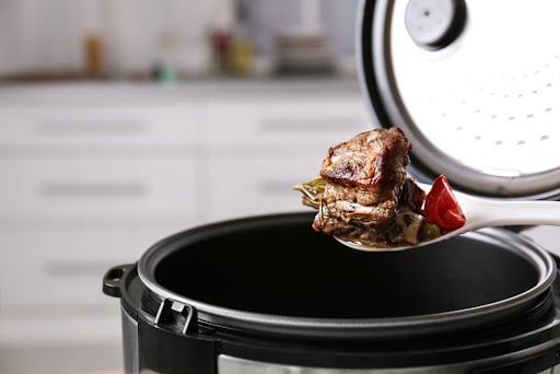 meat being pulled out of an instant pot