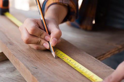 woman measuring board using tape measure